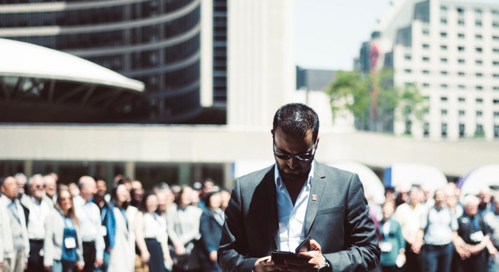 Focused businessman using tablet in a bustling crowd in Toronto's busy urban setting. — Get More Done with the Best Student H
