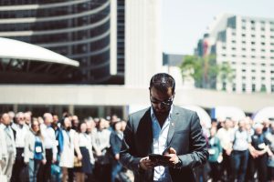 Focused businessman using tablet in a bustling crowd in Toronto's busy urban setting. — Get More Done with the Best Student H